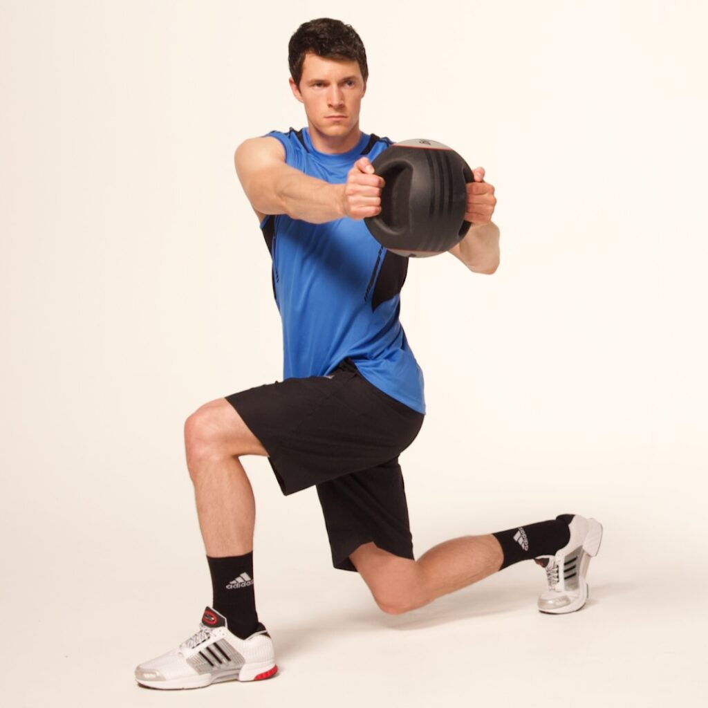 Variation image — athlete holding a light medicine ball while performing a Lunge and Twist to increase trunk load.