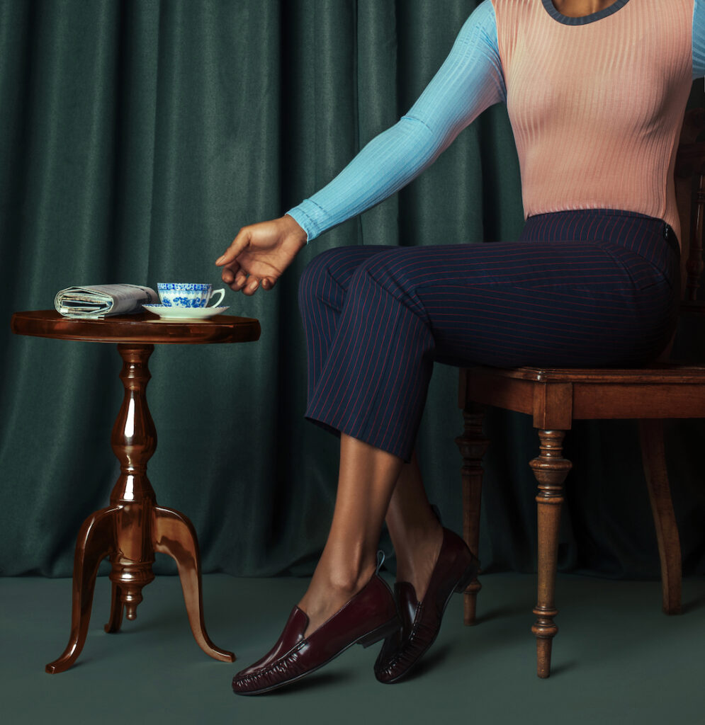 Shoe trends for spring. Elegant black woman sits down reaching for a cup of tea.