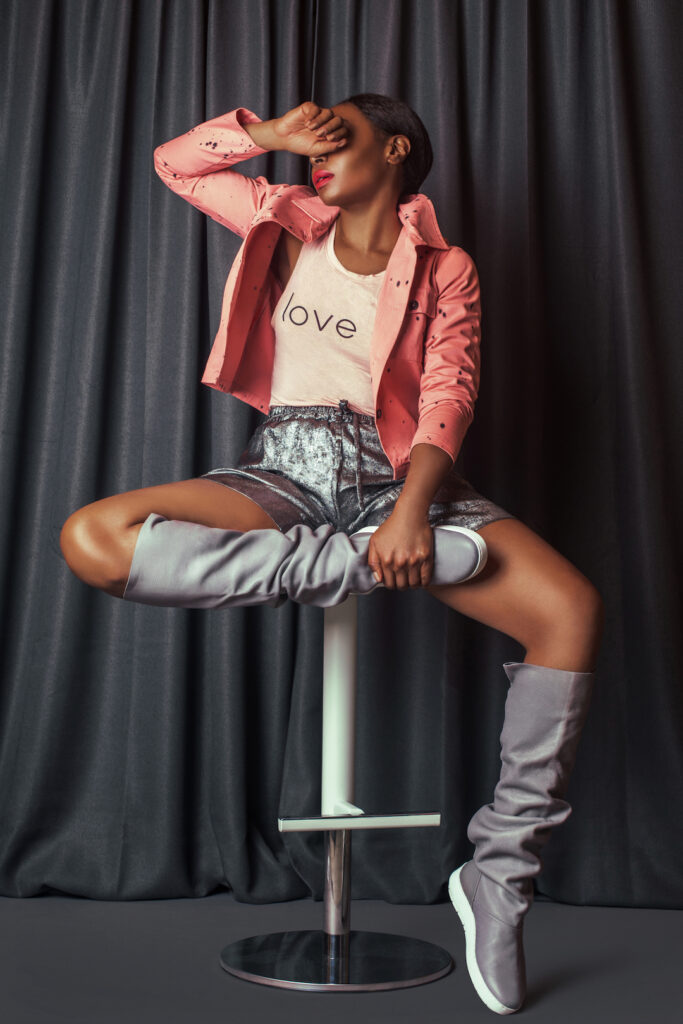 Spring boots for women. Black woman sitting on chair wearing silver boots.