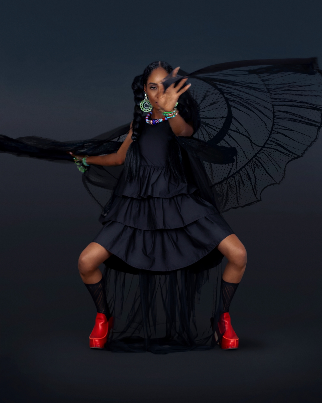 Maria posing in a flowing black dress with red shoes for a grunge boho fashion editorial
