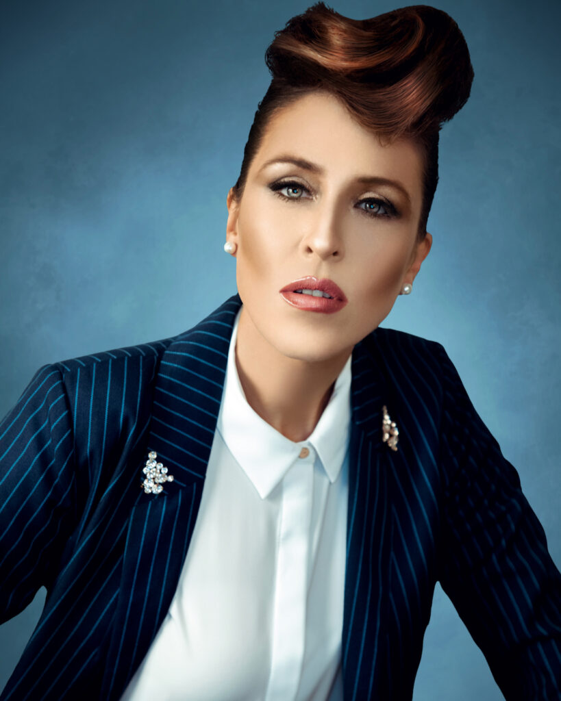 Britta Steffenhagen fashion editorial. Britta Steffenhagen standing indoors wearing a blue striped suit and white shirt.