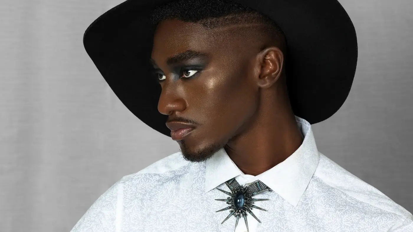 Pretty Boy Joy gender-fluid fashion editorial featuring a Black male model in a hat, white shirt and jewelry