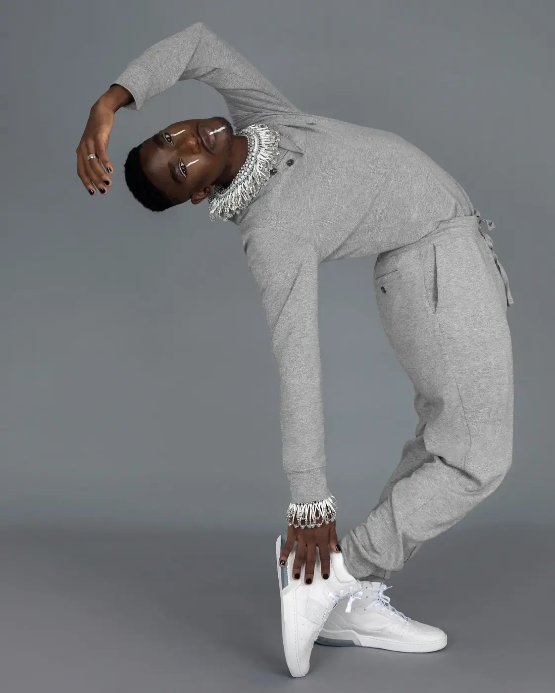 Grey tracksuit portrait combining athleisure and statement jewelry