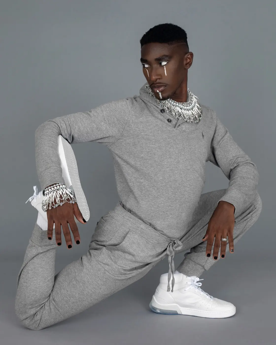 Relaxed grey tracksuit pose in a minimalist studio setting