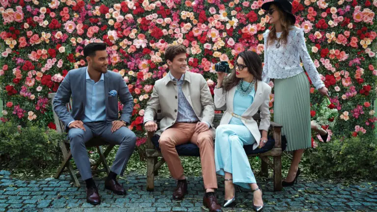 Fashion editorial cast posing in front of a wall of colorful flowers