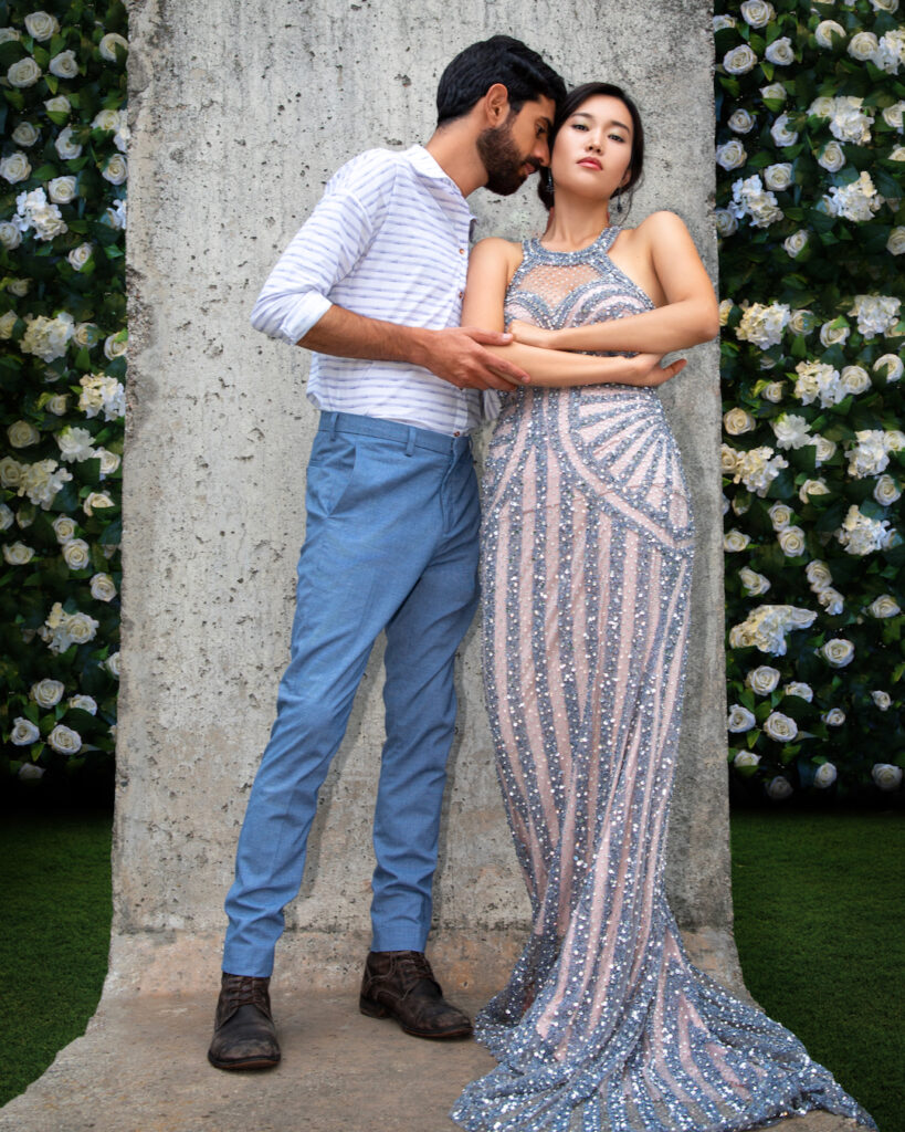editorial wedding photography. Portrait of an interracial couple surrounded by flowers, wearing elegant wardrobe suitable for a wedding.