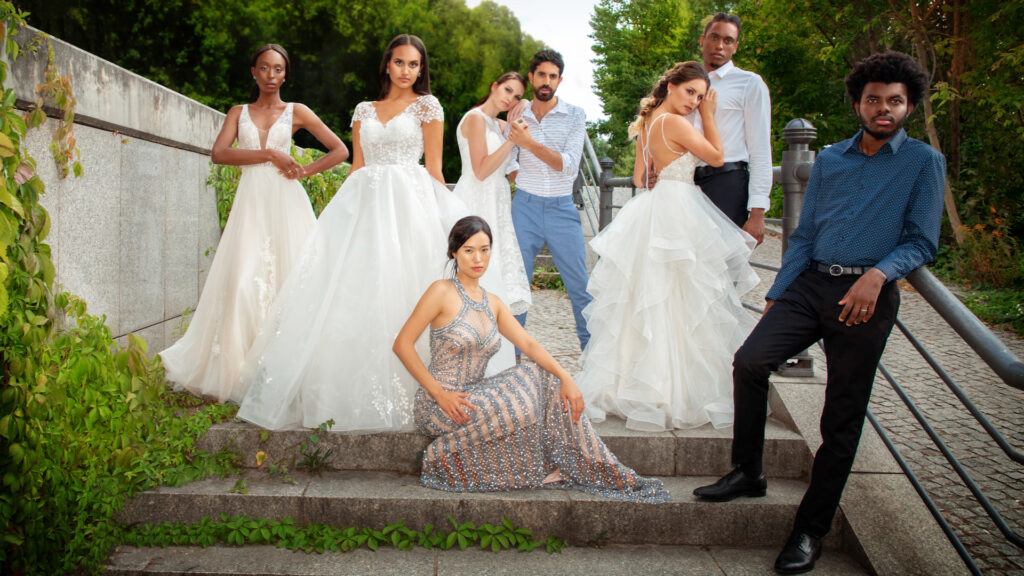 editorial wedding photography. Portrait of three couples and an additional woman standing together on stone steps in elegant outfits suitable for a wedding.
