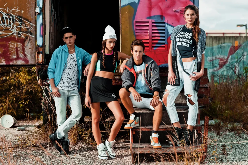 Four models wearing layered urban fashion on the steps of a graffiti-covered trailer in Miami