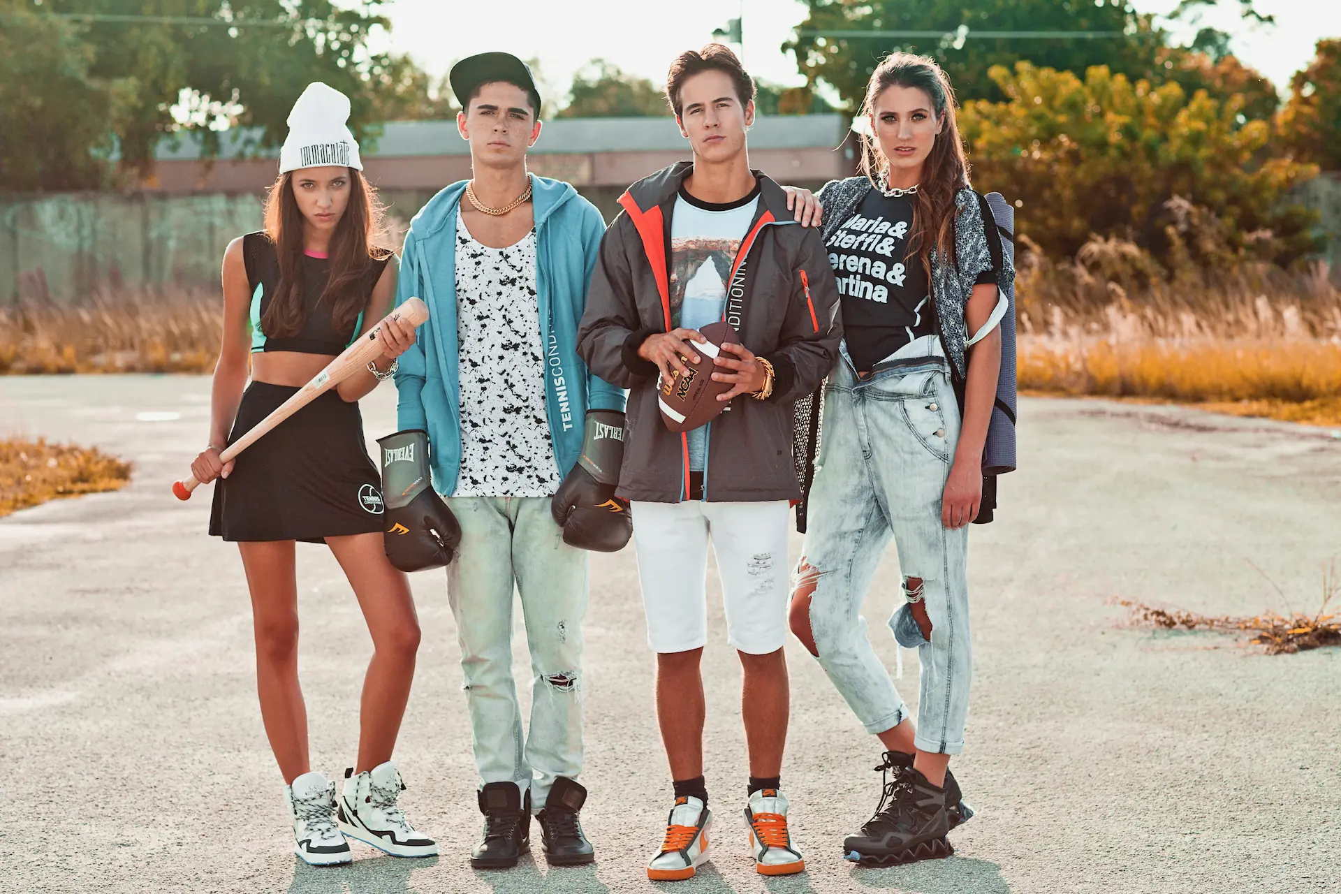 Four models in sport-inspired Miami streetwear posing outdoors in warm afternoon light