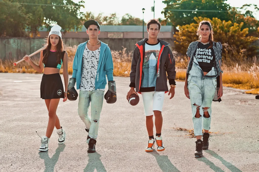 Four models in sporty Miami streetwear walking across an open lot in warm afternoon light
