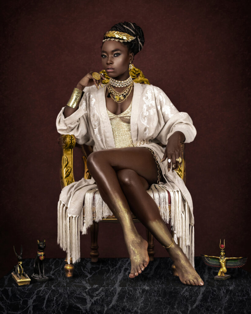 Avantgarde Fashion - Black woman in majestic dress with golden jewelry and Egyptian artifacts