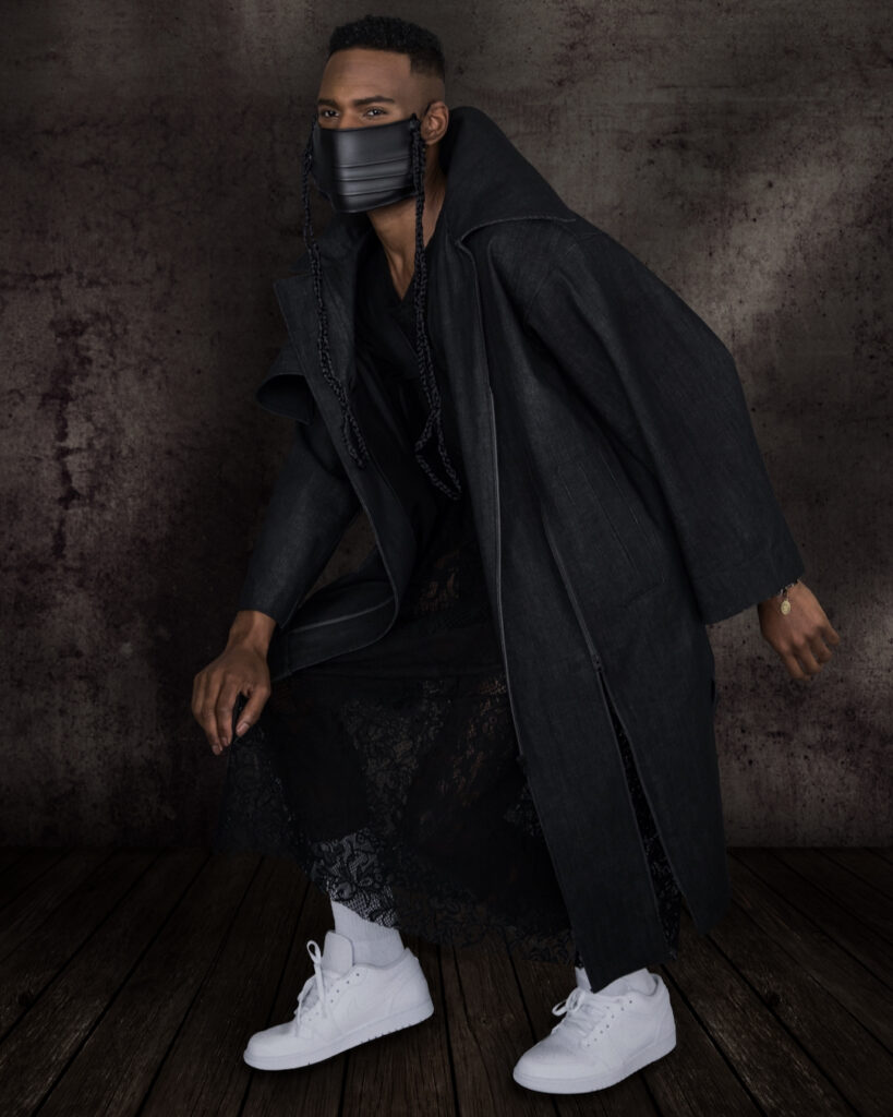 Avantgarde Fashion - confident Black man wearing leather face mask, denim coat and black dress