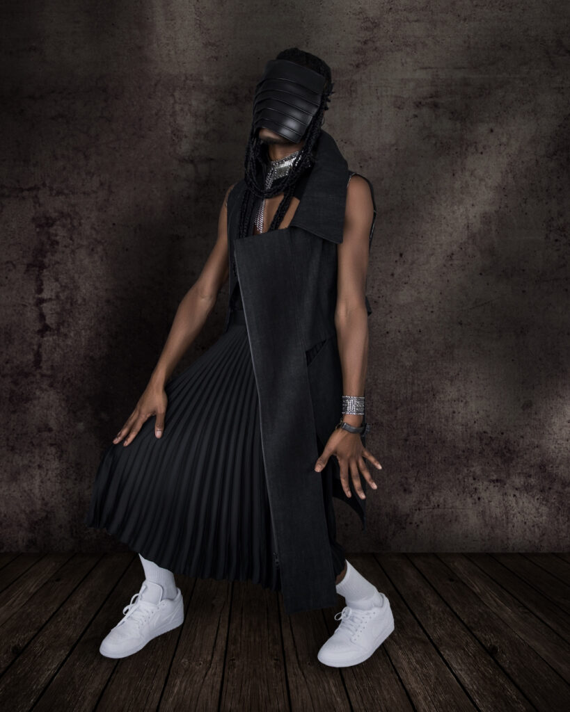 Avantgarde Fashion - serene Black man wearing leather mask, sleeveless coat and black dress