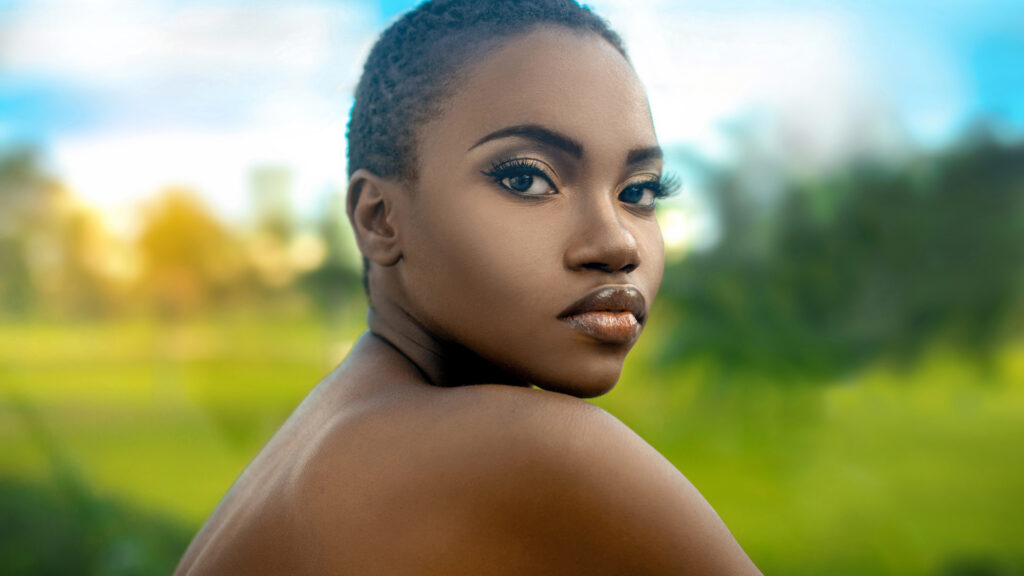 Artistic beauty photography portrait of a sexy young Black female with short hair and beautiful makeup in tropical surroundings.