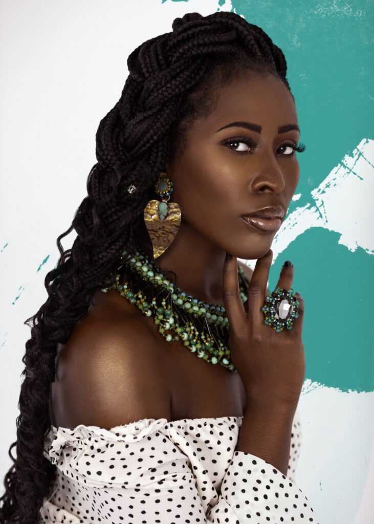 Artistic beauty photography portrait of a sensual young Black female in a white shoulder-free top with green and black jewelry.