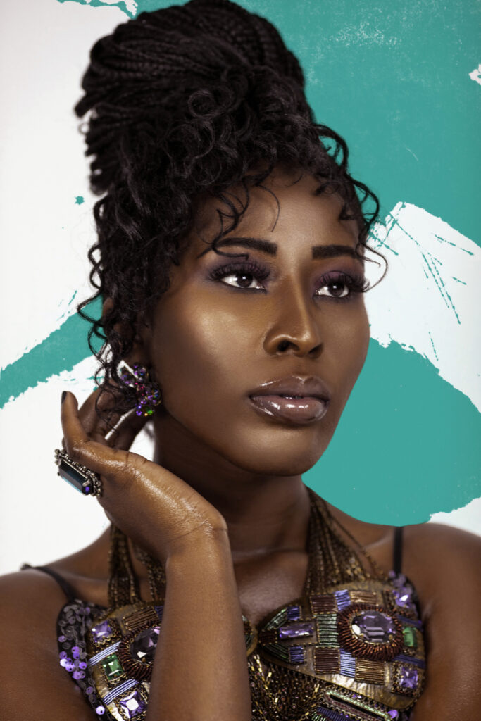 Closeup artistic beauty photography portrait of a serene Black female wearing a colorful necklace and earrings in a studio.