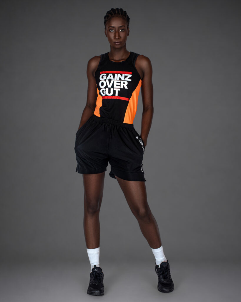 Gigi standing in black and orange athletic wear with black shorts for an athleisure fashion editorial