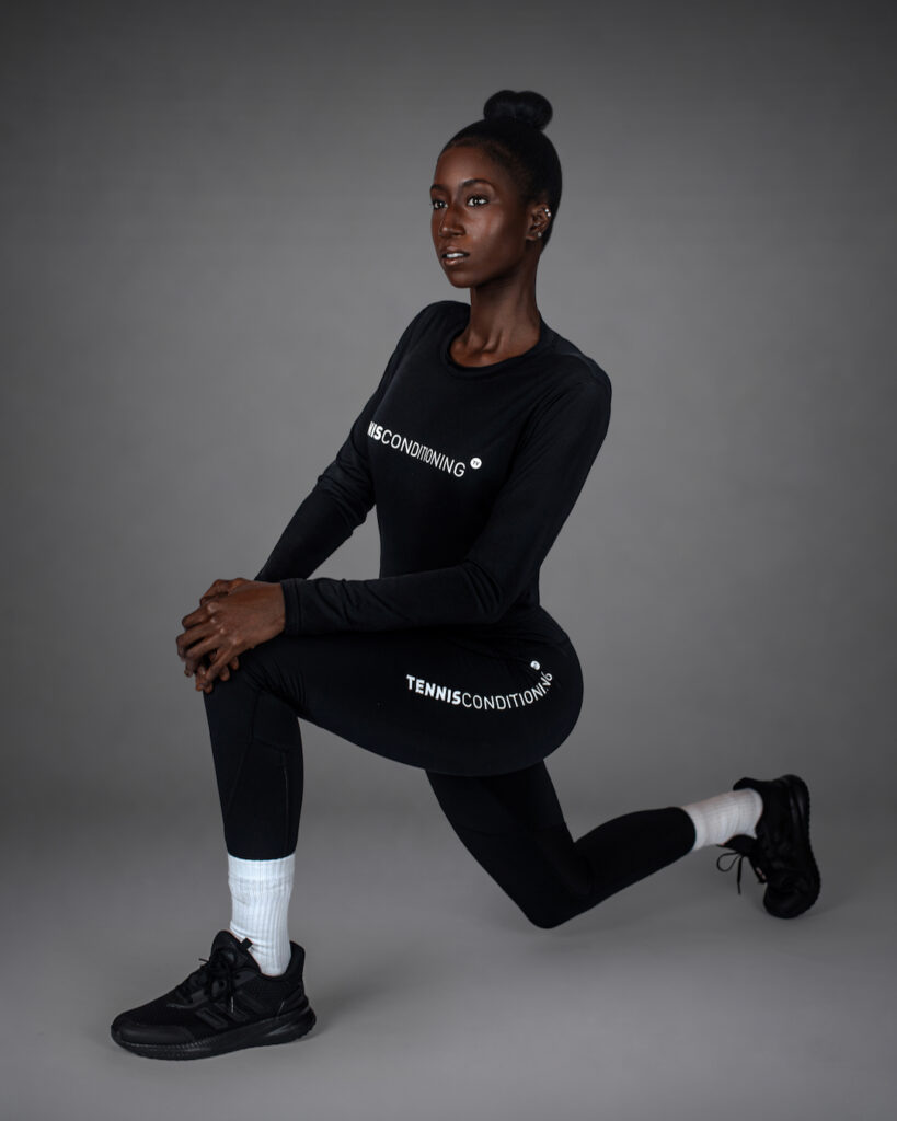 Gigi kneeling in fitted black athletic clothing with white socks and black sneakers