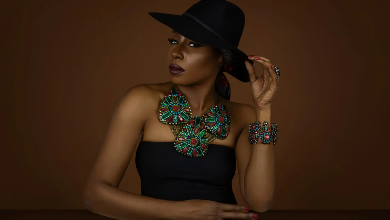 Black woman in a black hat wearing colorful Konplott statement jewelry