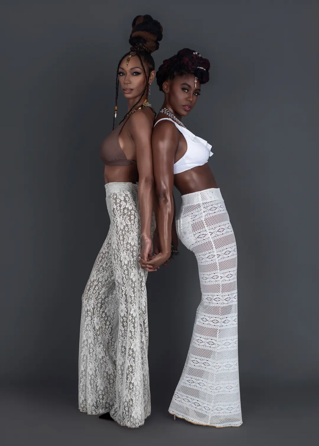 Two Black fashion models in coordinated white looks expressing energy and consistency