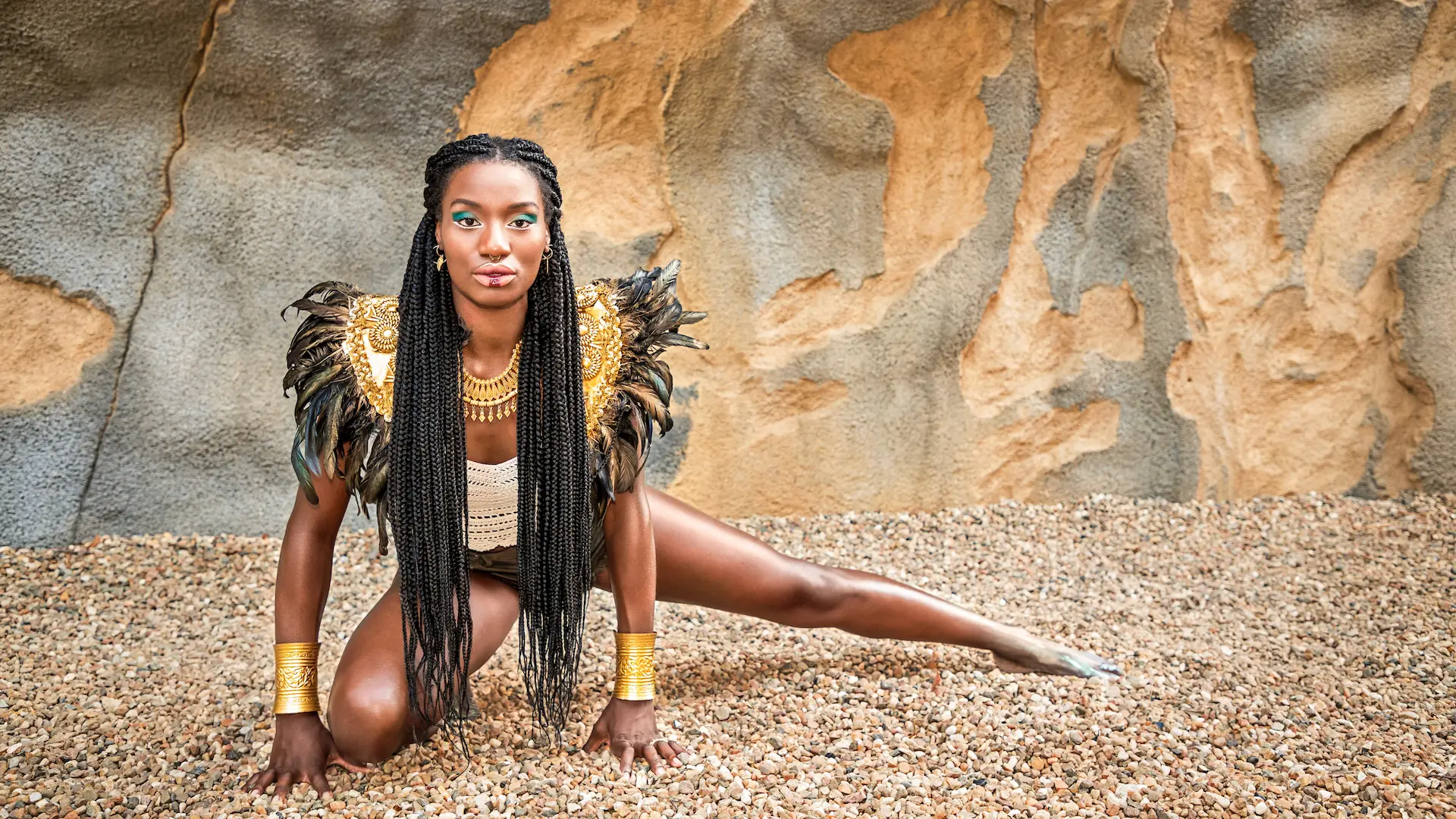 Woman posed against a stone wall in a black feathered fashion look