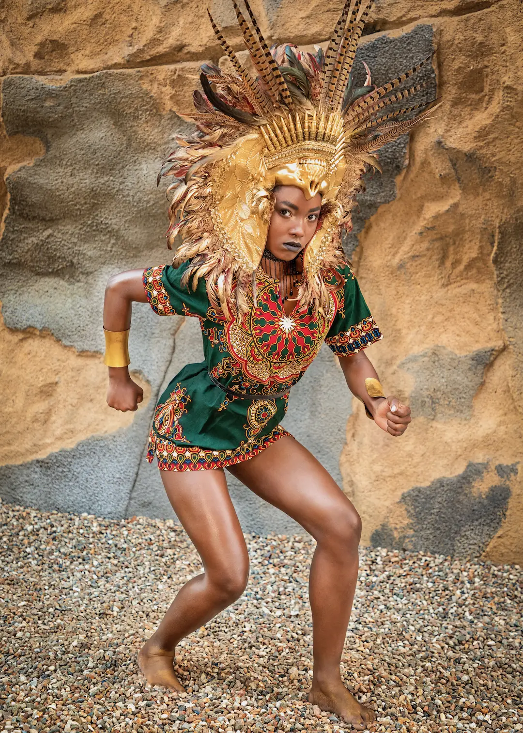 Woman in an elaborate sculptural headpiece posing against a stone backdrop