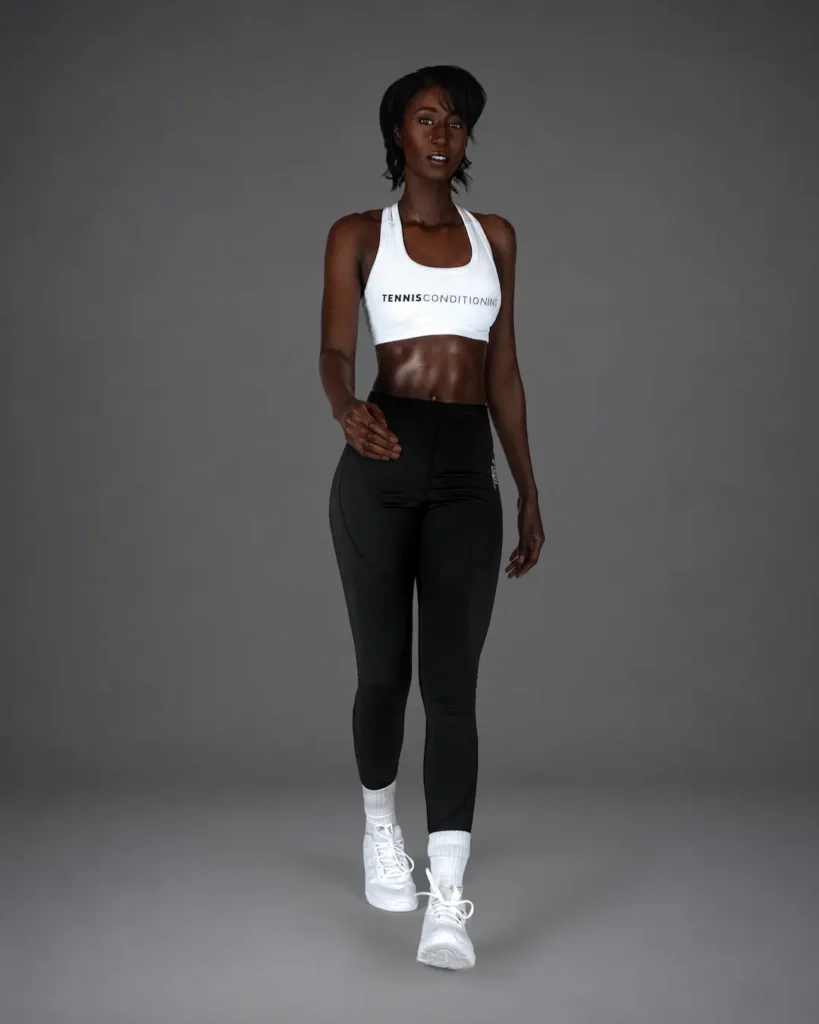 Gigi stepping forward in a white sports bra and black leggings during an athletic fashion studio shoot