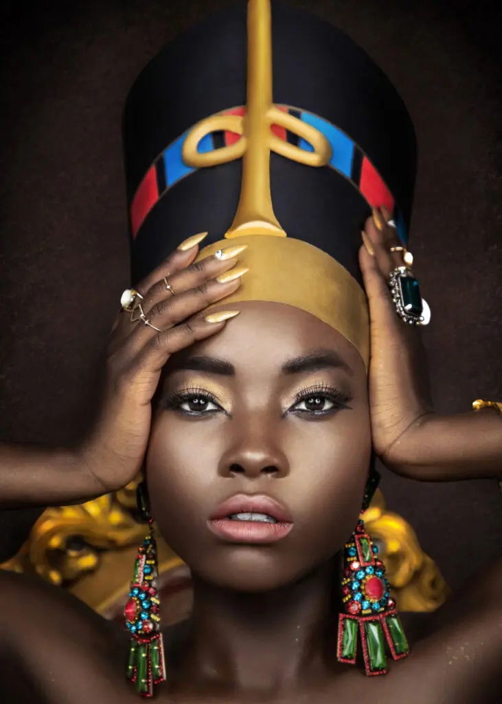 Black woman wearing an Egyptian-inspired crown and colorful statement earrings