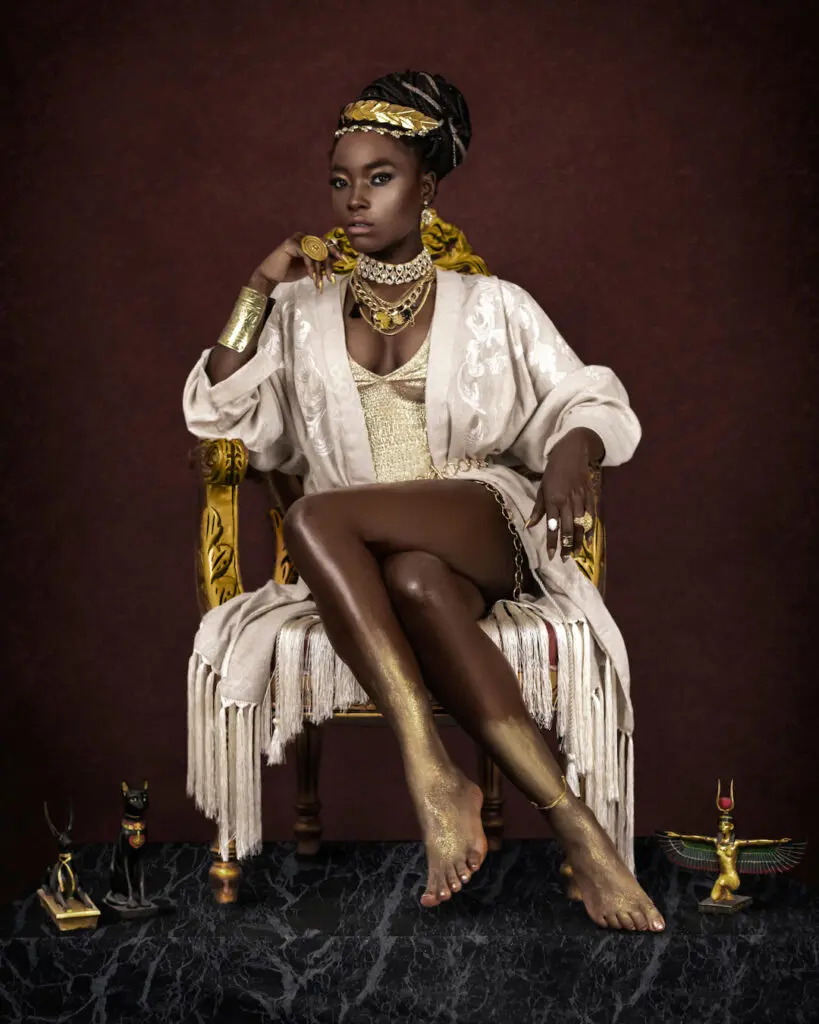 Black woman in a sculptural dress with gold jewelry and Egyptian-inspired objects