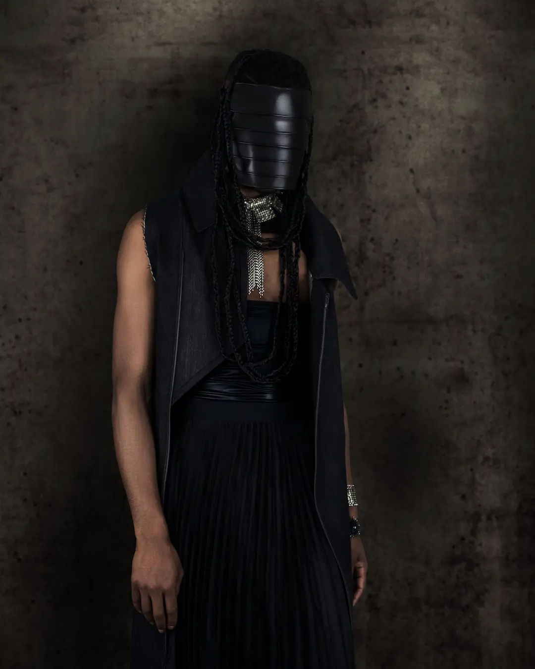 Black woman in a black avant-garde dress and silver jewelry against a dark studio background