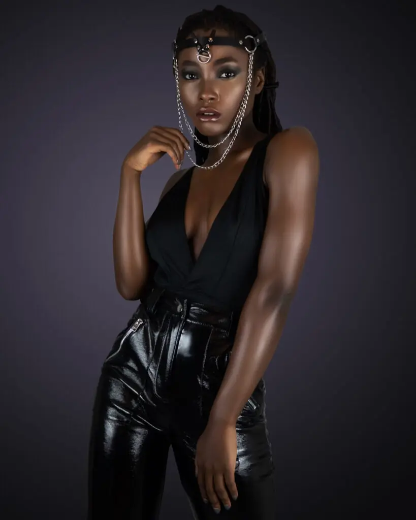 Black woman in a sleeveless black top, leather trousers and silver jewelry