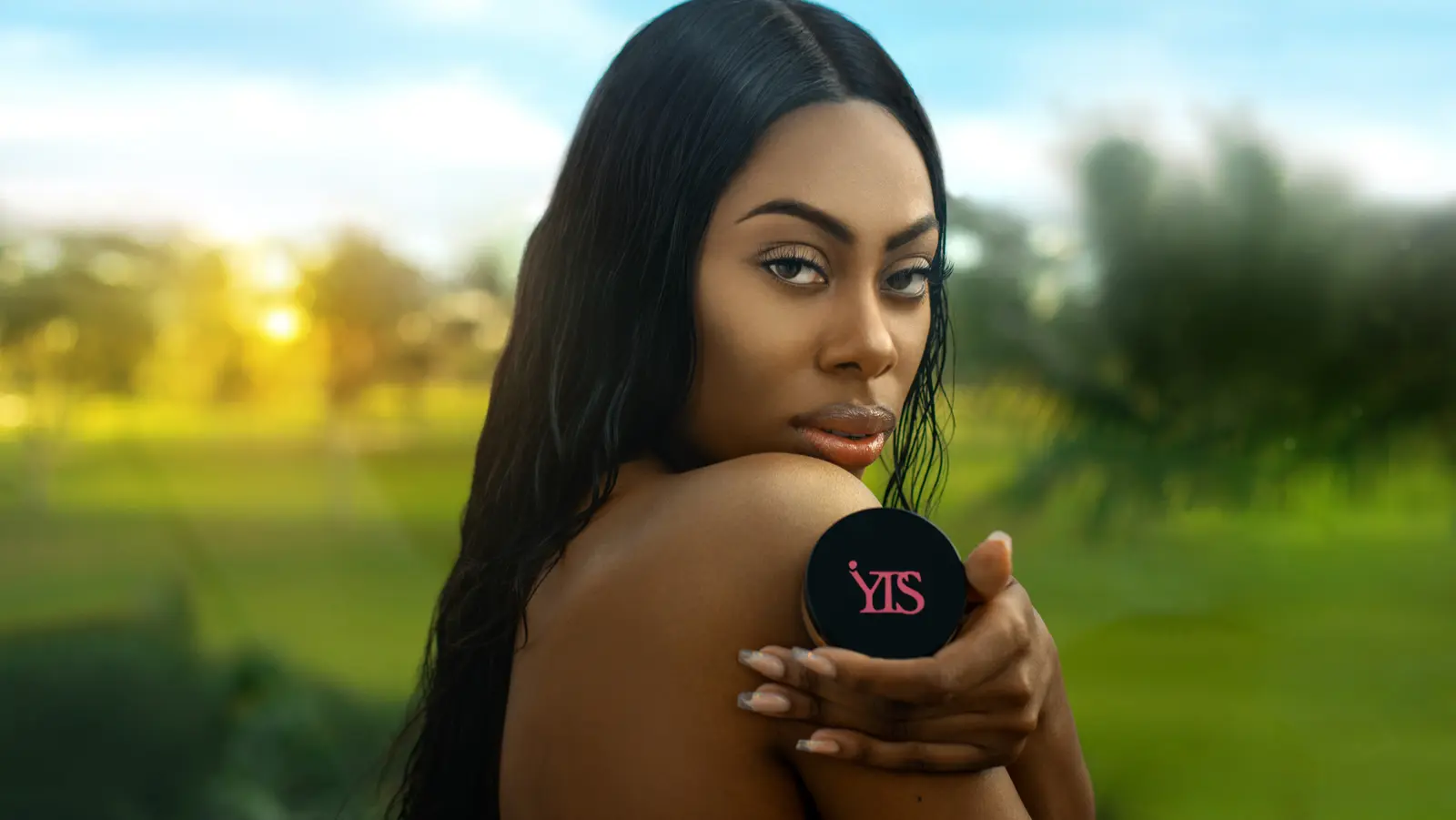 Model holding a round beauty powder compact in an outdoor campaign portrait