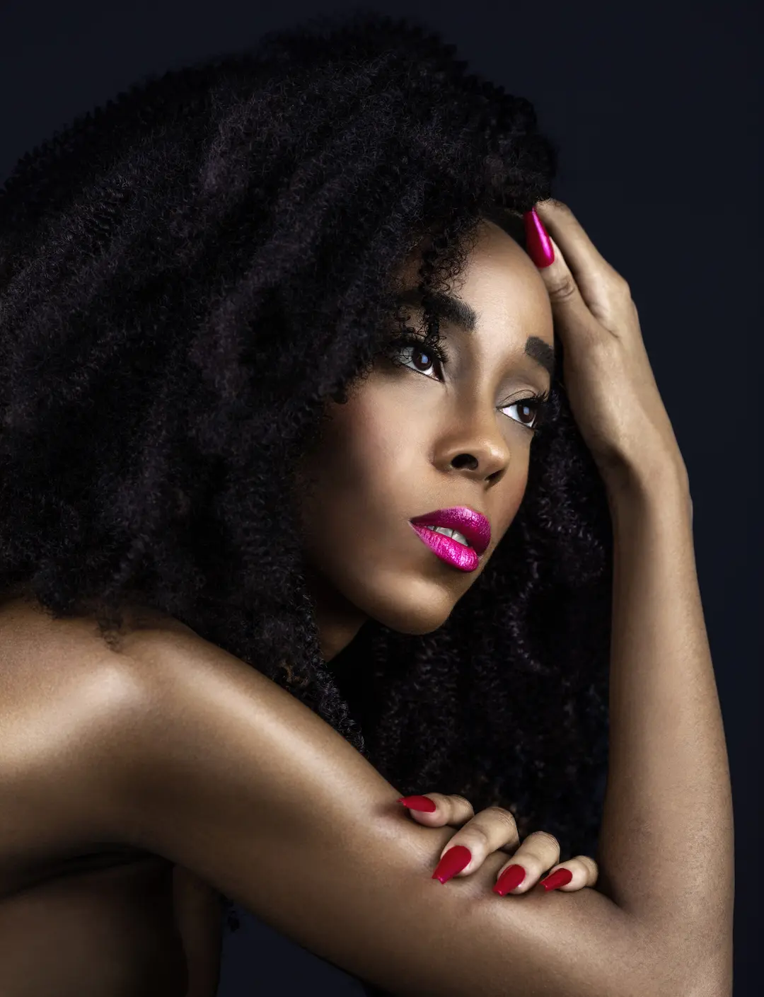 Bold fuchsia lip paired with minimal eye makeup and natural curls