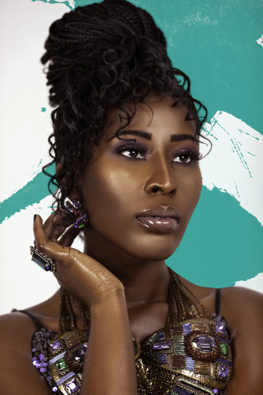 Close-up portrait of a Black woman wearing colorful statement jewelry against a clean studio background.
