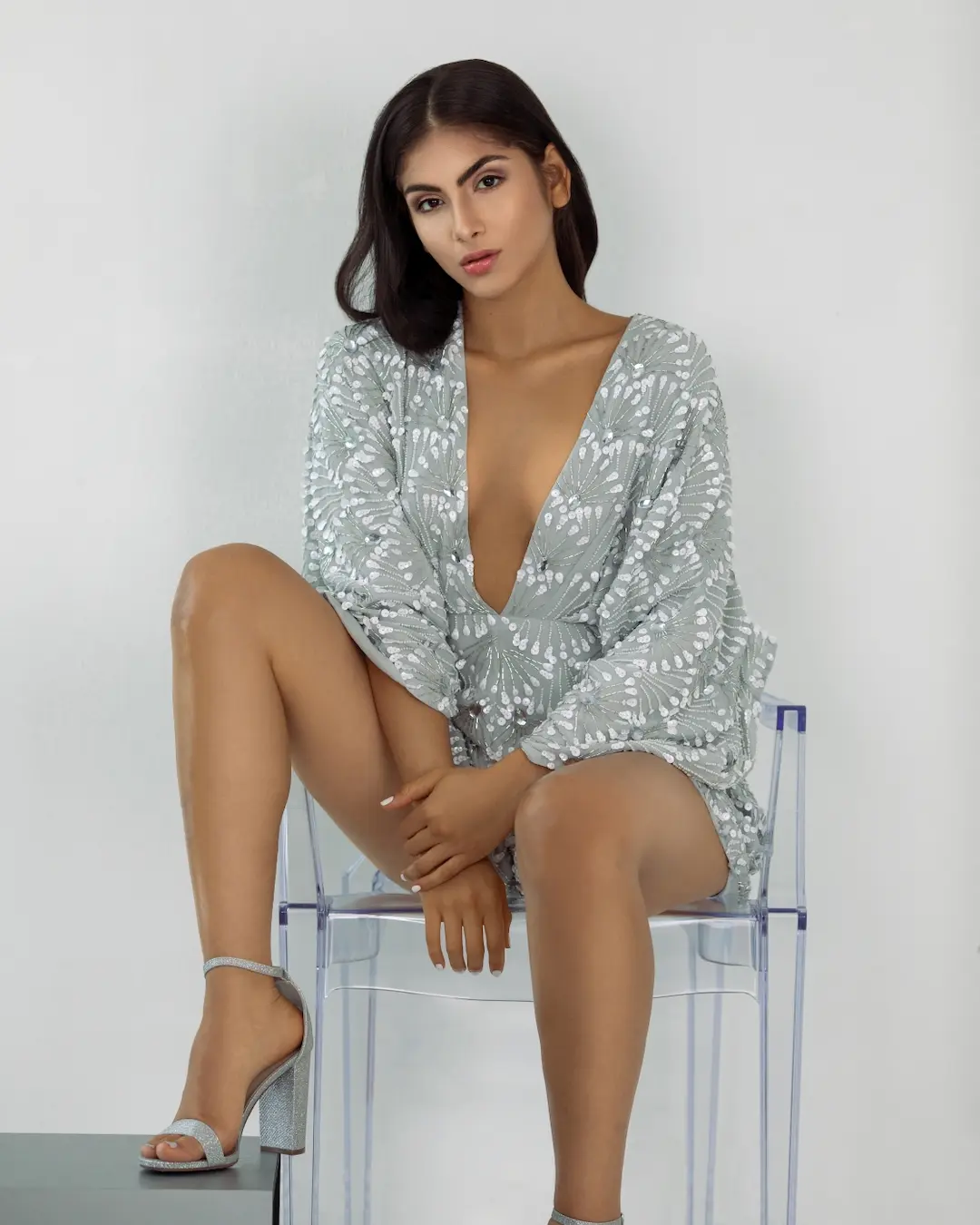 Seated fashion portrait featuring a reflective silver mini dress
