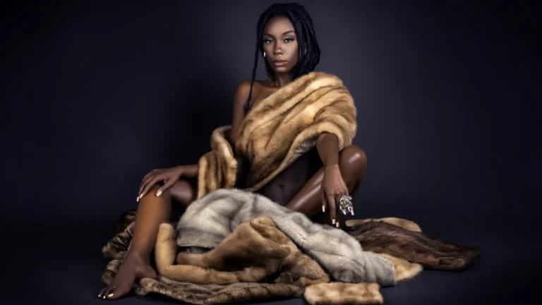 Black model with long locs reclining in a fur coat for the Locks of Beauty fashion editorial