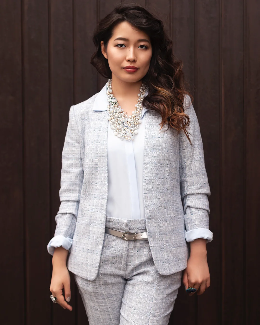 Fashion portrait of a woman in a gray suit against a wooden backdrop