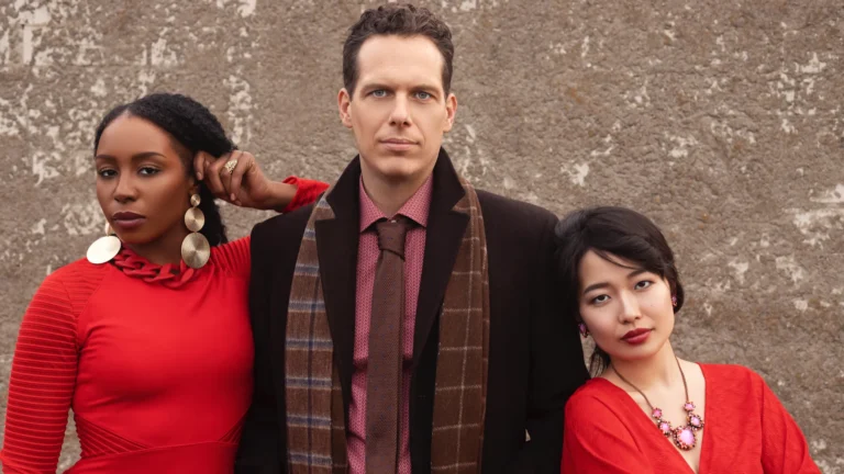 Three fashion subjects posing against a textured wall outdoors