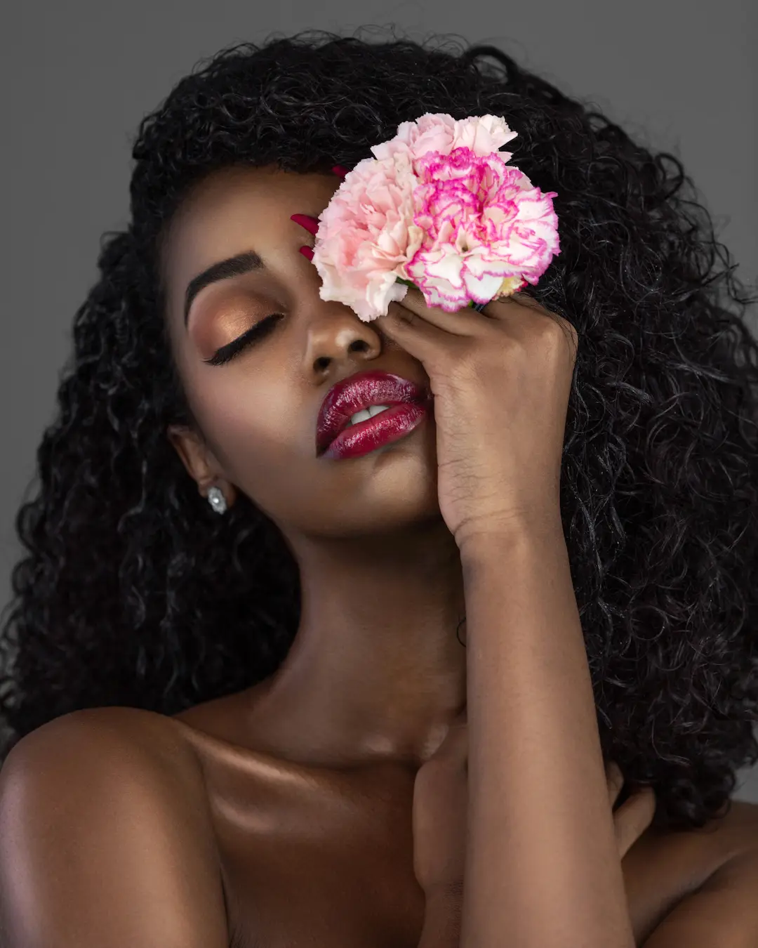 Close-up Black beauty portrait with a pink flower covering one eye