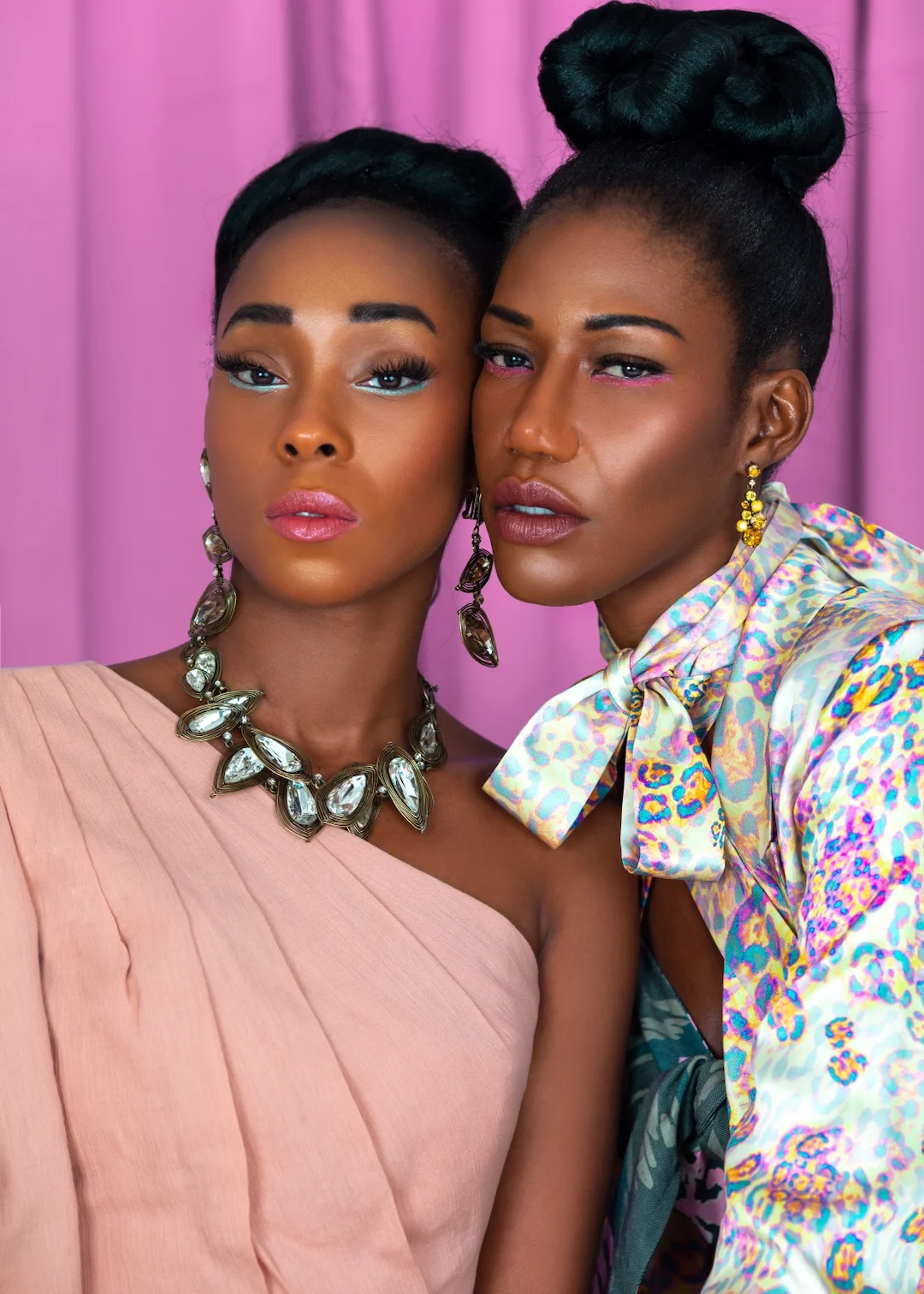 Vanessa and Claudine pose together in jewel-tone outfits with statement jewelry.