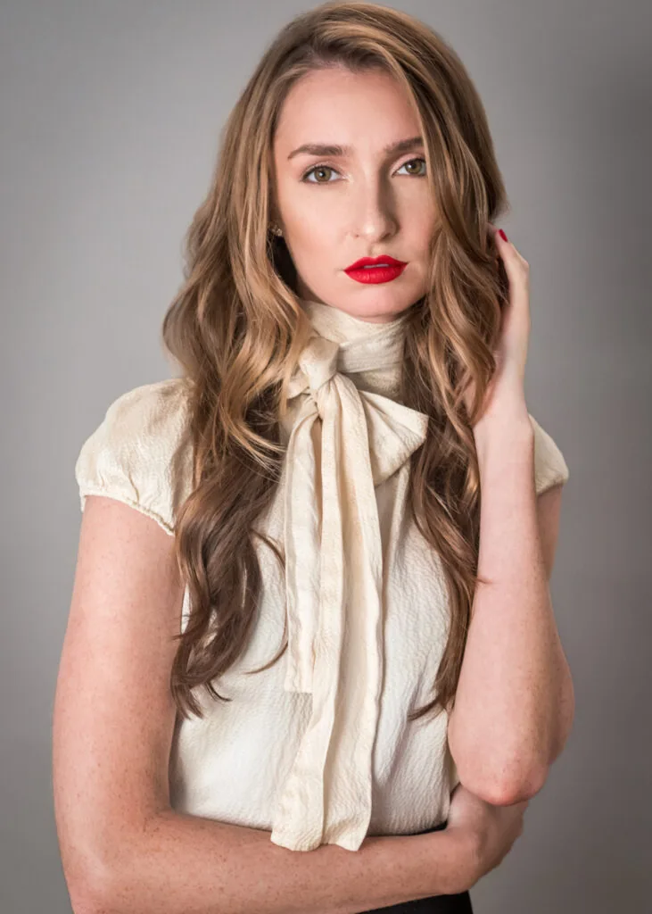 Beauty portrait of a model in a cream blouse with red lipstick