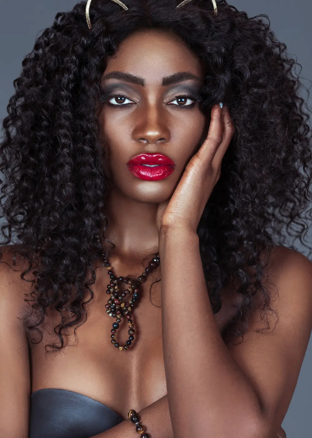 Beauty portrait of a Black woman with red lips, dramatic eye makeup and statement jewelry