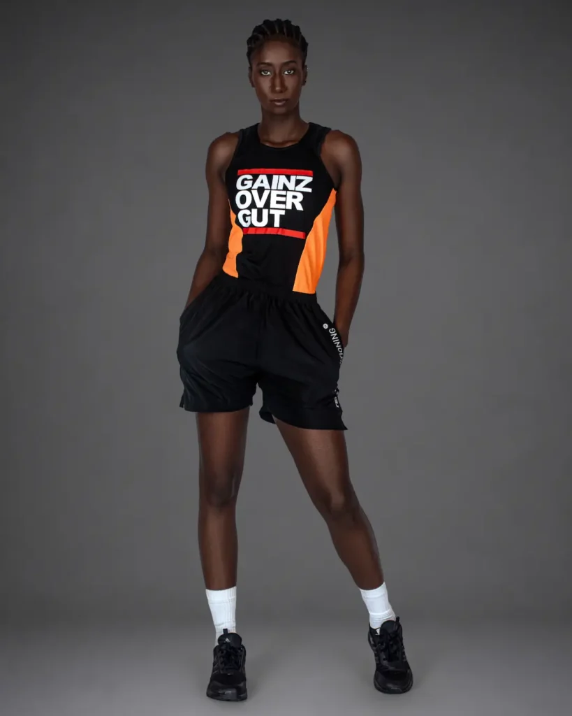 Gigi standing in black and orange athletic wear with black shorts for an athleisure fashion editorial