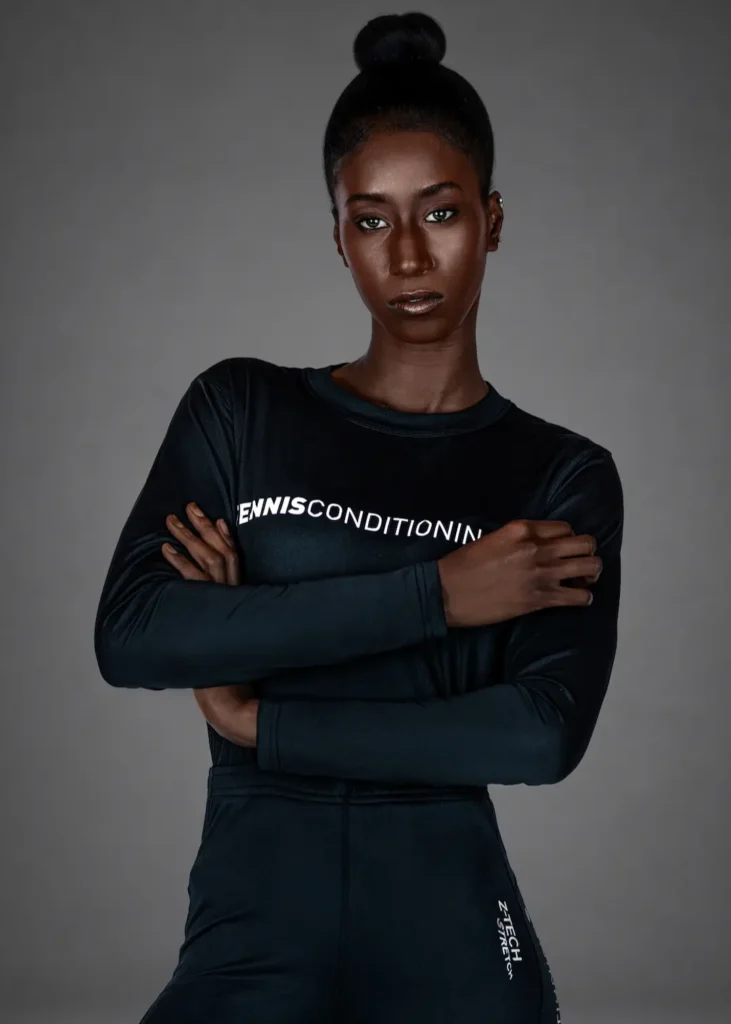 Portrait of Gigi with folded arms wearing black long-sleeve activewear against a gray studio background