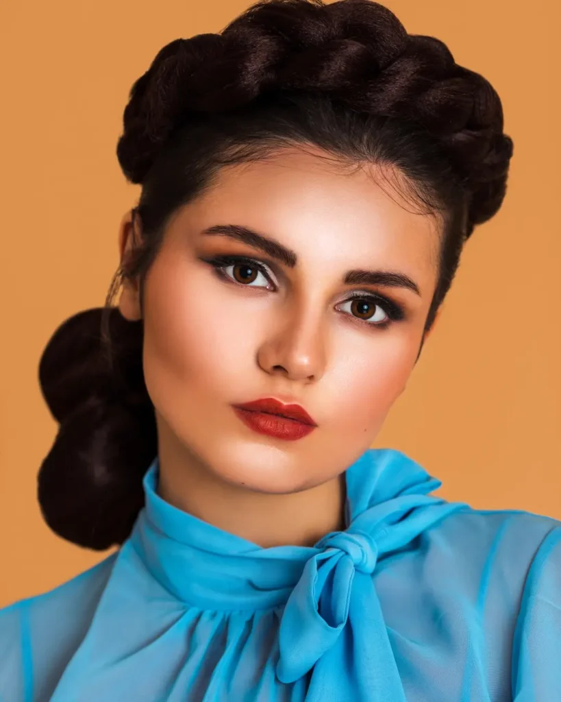 Close beauty portrait of Mariana in blue chiffon with braided hair and red earrings