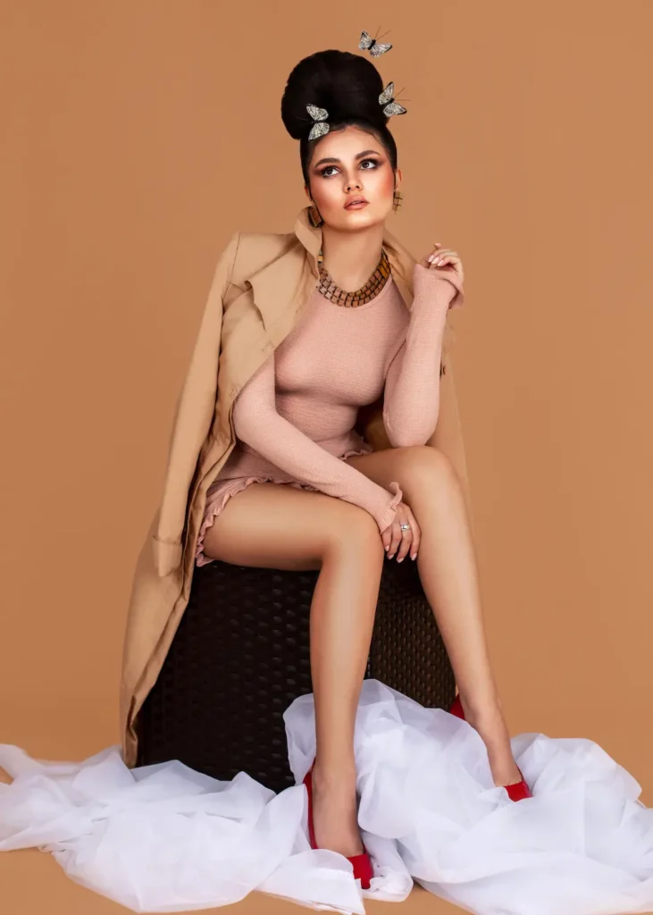 Mariana seated in a blush pink look with butterflies in her hair