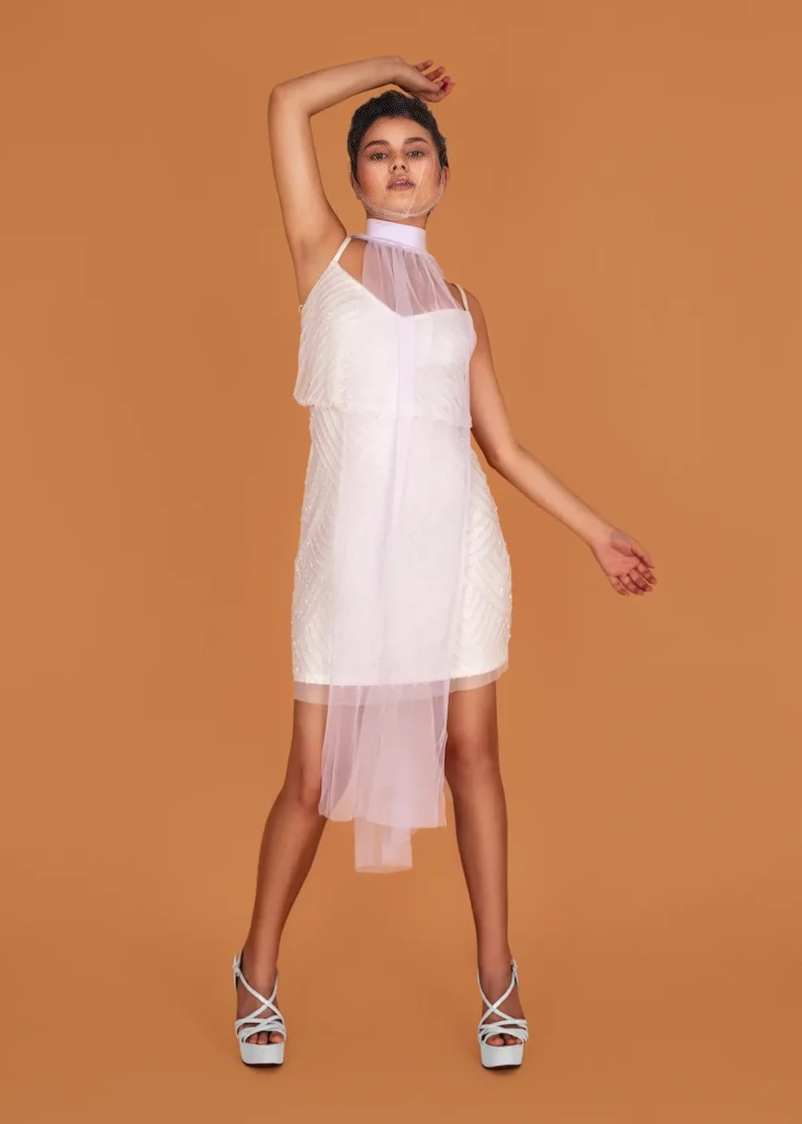 Mariana moving in a layered white dress with one arm raised in the studio