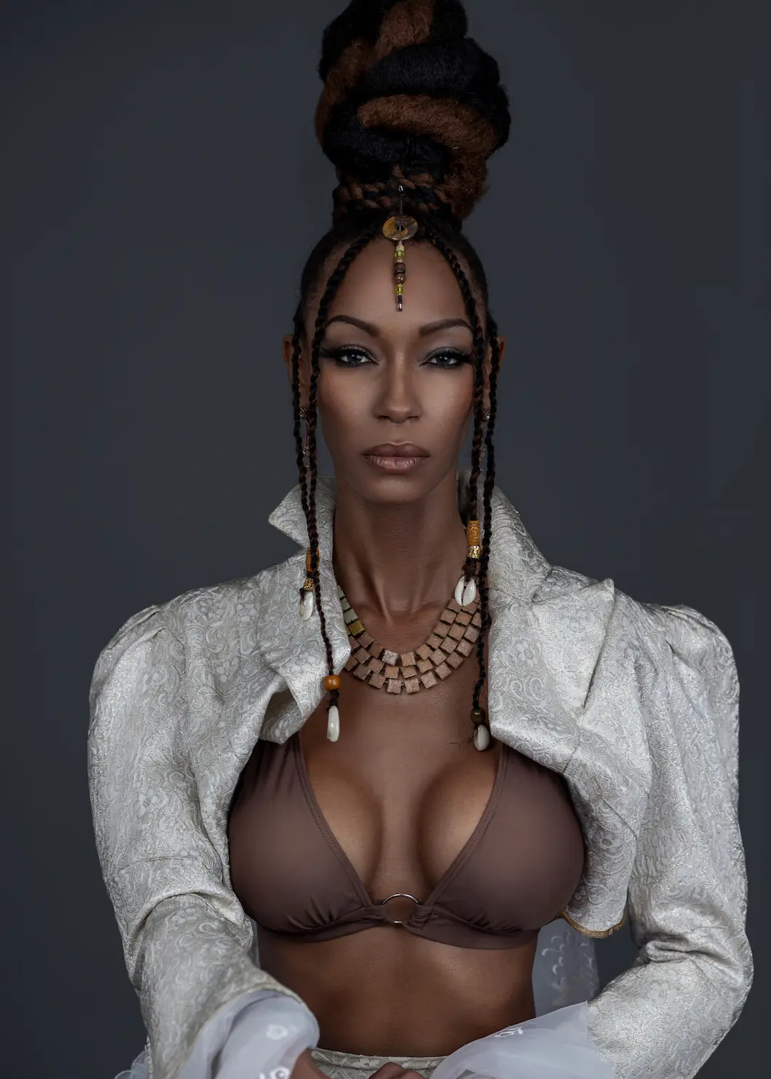 Lola Chel in a white tailored jacket, brown top and statement jewelry