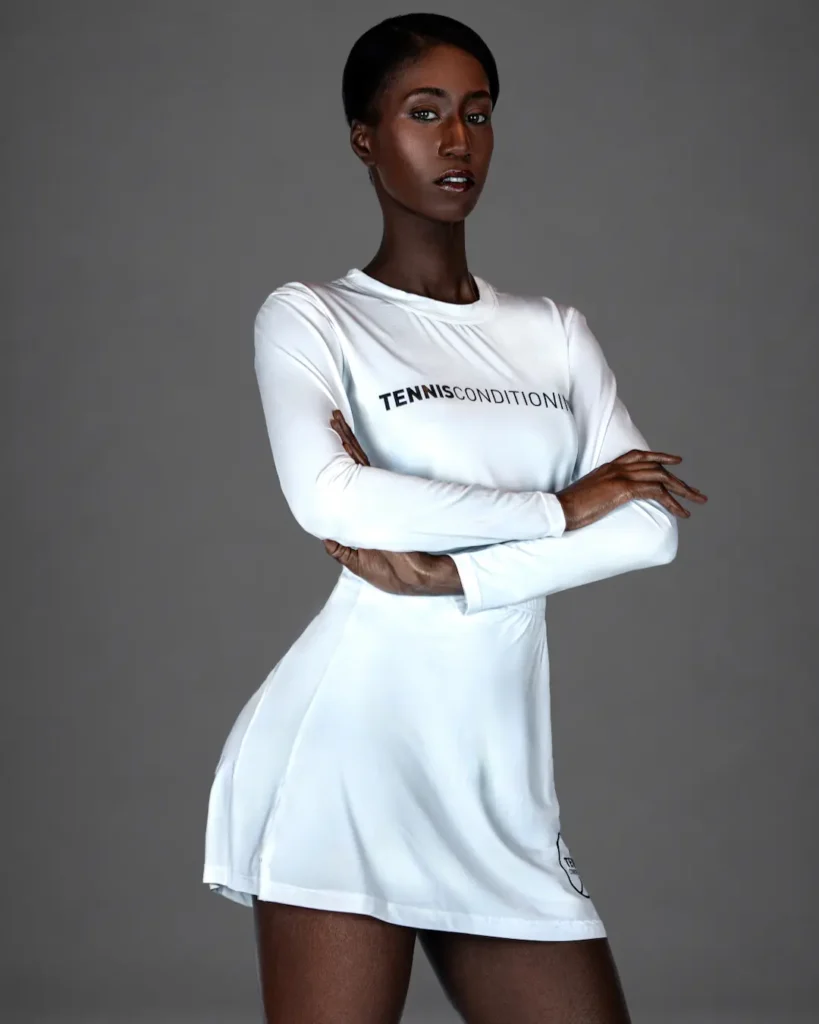 Gigi wearing a white long-sleeve tennis-inspired outfit in the Strength in Motion fashion editorial