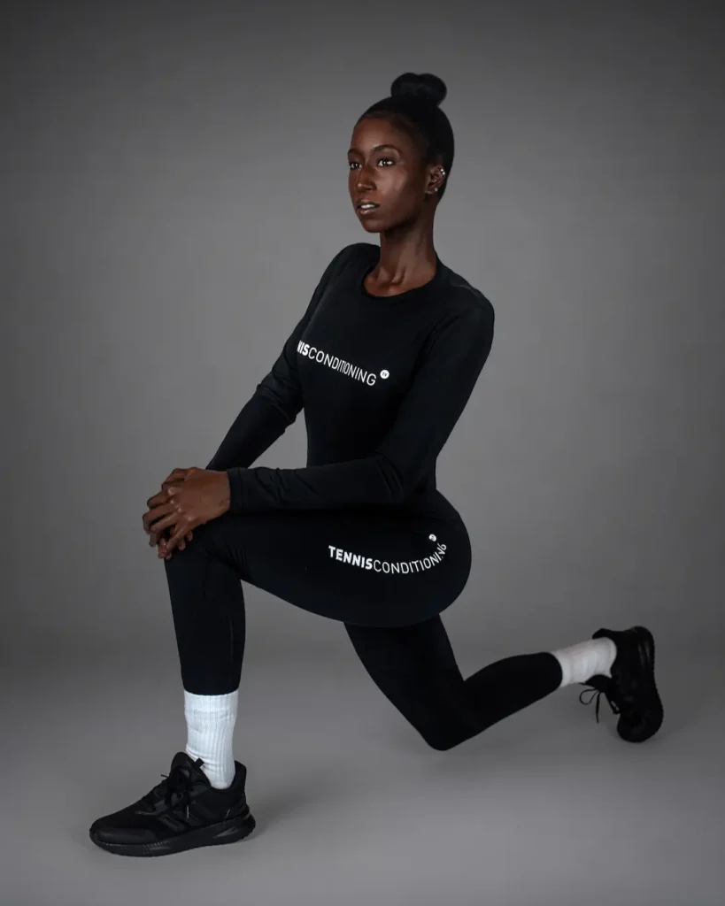 Gigi kneeling in fitted black athletic clothing with white socks and black sneakers
